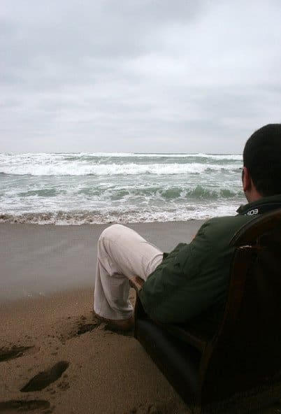Sitting on a chair at a sand beach, on a cloudy day, looking to the sea.