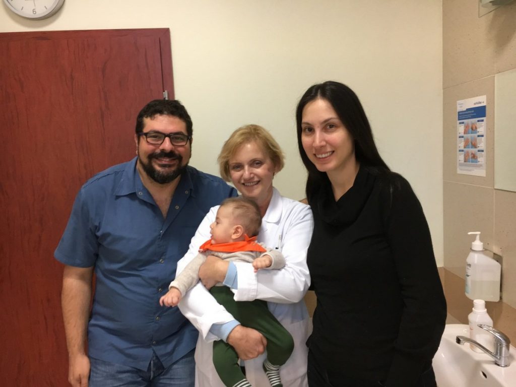 Pediatrician holding our 4-month-old son and posing with mom and dad